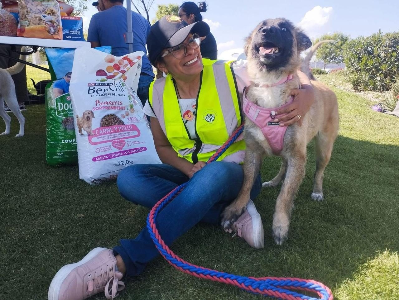 Voluntaria con un costal de alimento donado junto a un perro rescatado